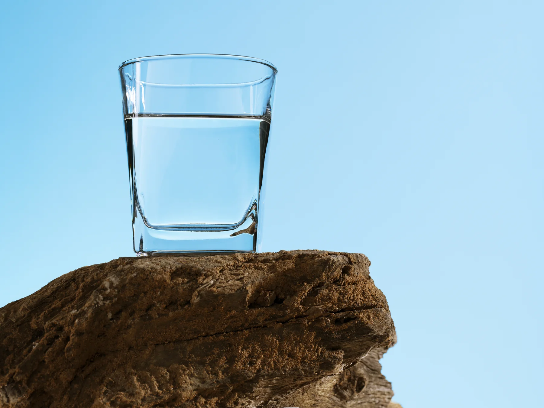 A glass of water resting on rock against open sky